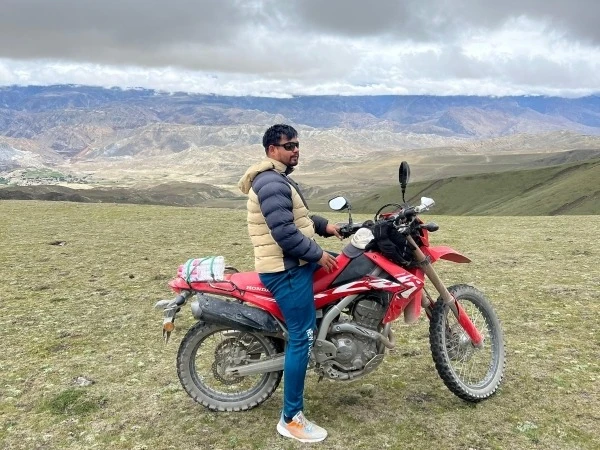 Motorcyclist riding a dirt bike across the high-altitude landscape of Upper Mustang, Nepal