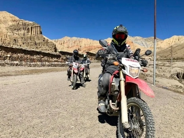 Motorcyclists riding through the rugged, arid landscapes of Upper Mustang, Nepal, on an adventure motorcycle tour.