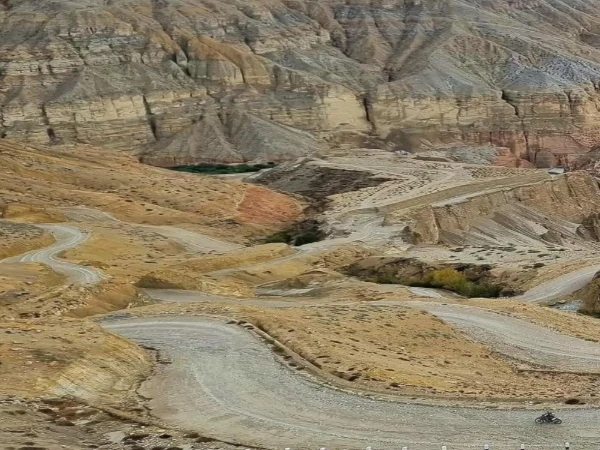 Motorcycle rider on a rugged winding road through the barren Himalayan landscape of Upper Mustang, Nepal