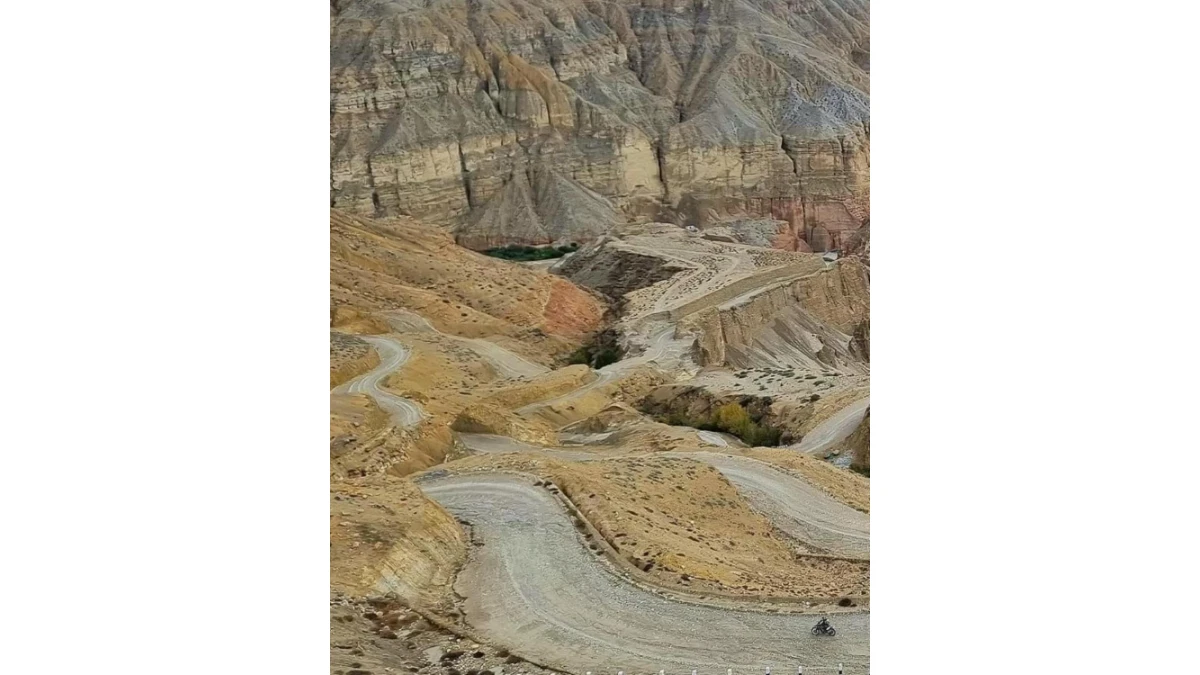 Motorcycle rider on a rugged winding road through the barren Himalayan landscape of Upper Mustang, Nepal