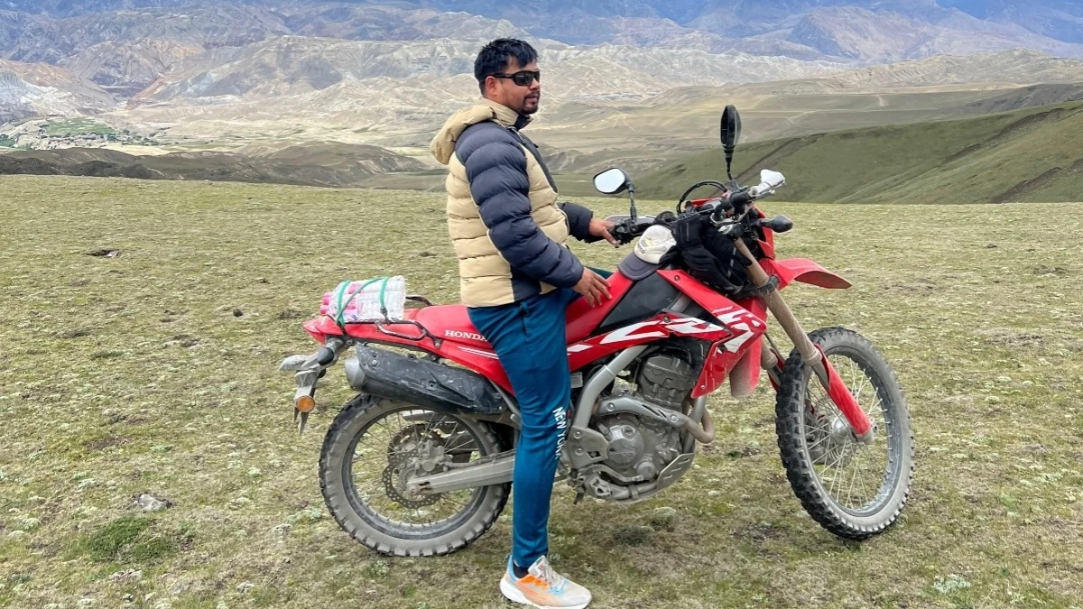 Motorcyclist riding a dirt bike across the high-altitude landscape of Upper Mustang, Nepal