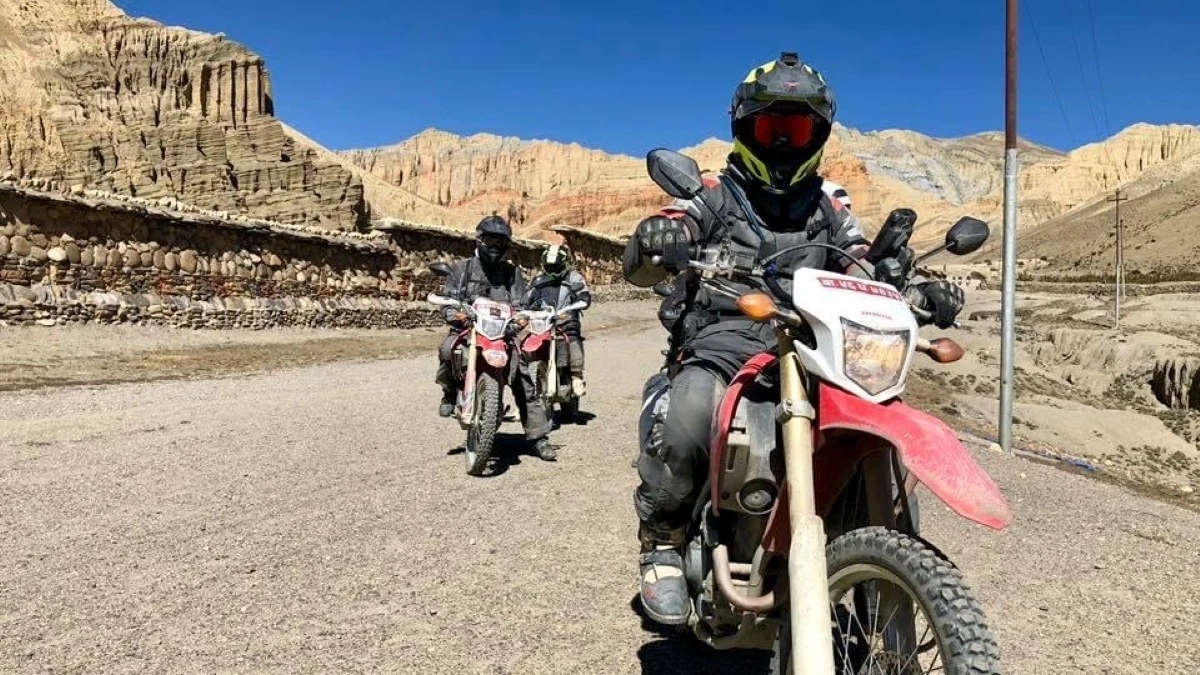 Motorcyclists riding through the rugged, arid landscapes of Upper Mustang, Nepal, on an adventure motorcycle tour.